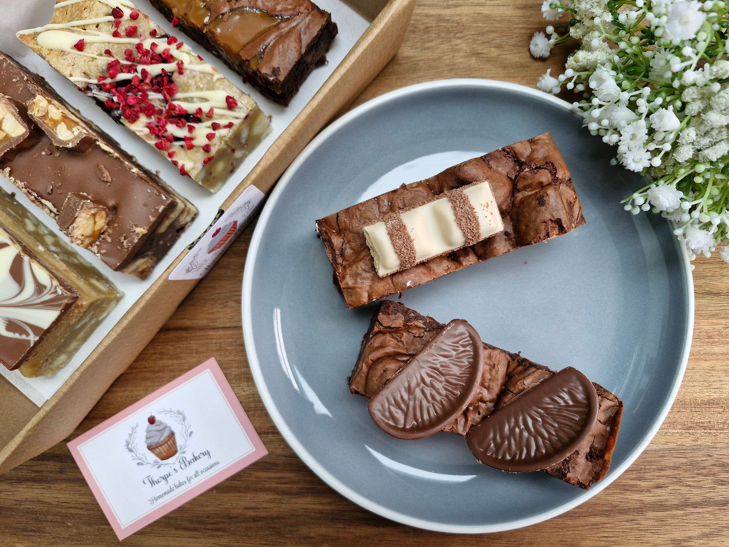 Assorted baked slices on a plate next to a Thorpe’s bakery treat box containing further bakes.