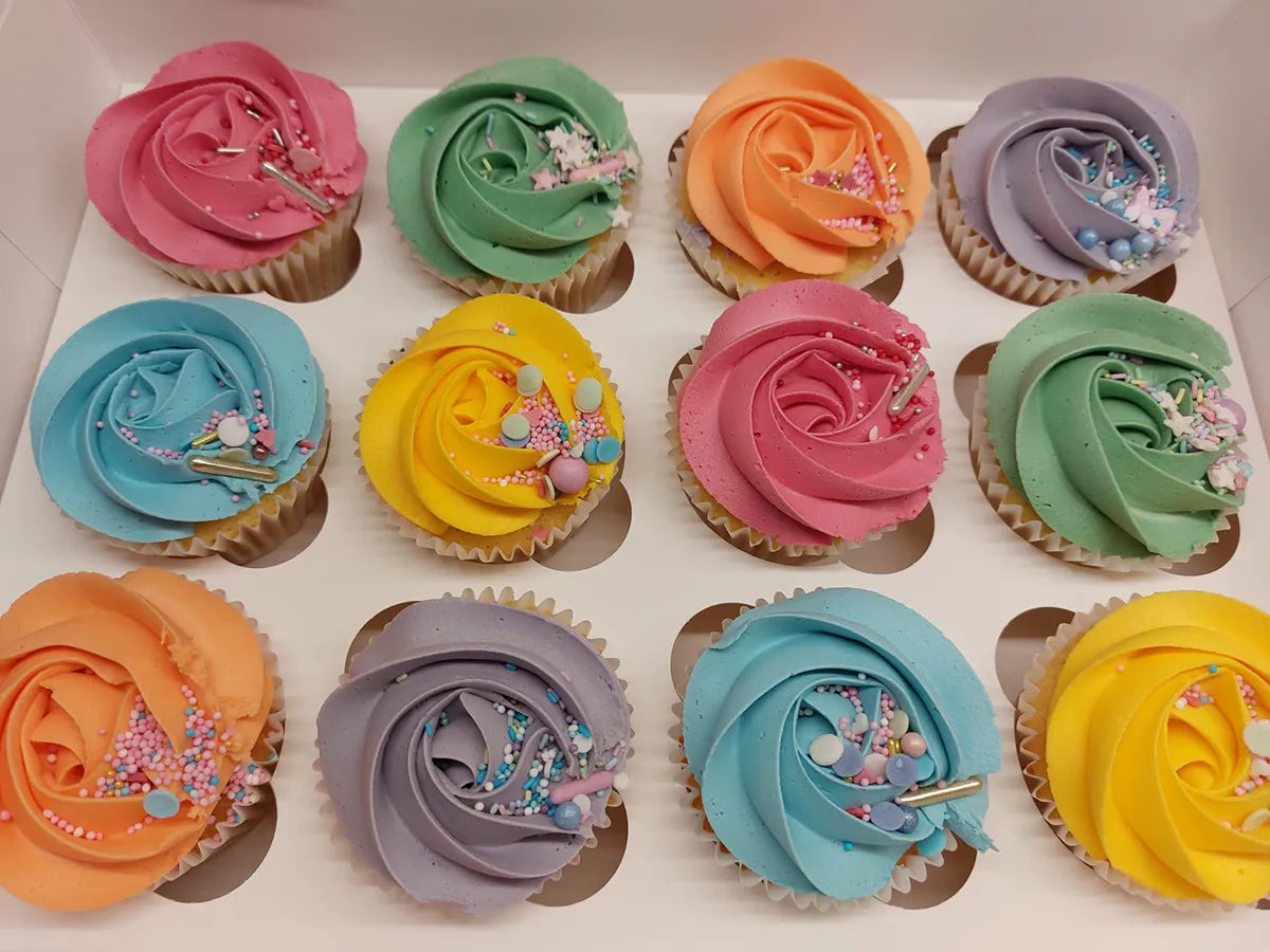 Hand-decorated cupcakes topped with blue, green, yellow and pink buttercream and sprinkles.