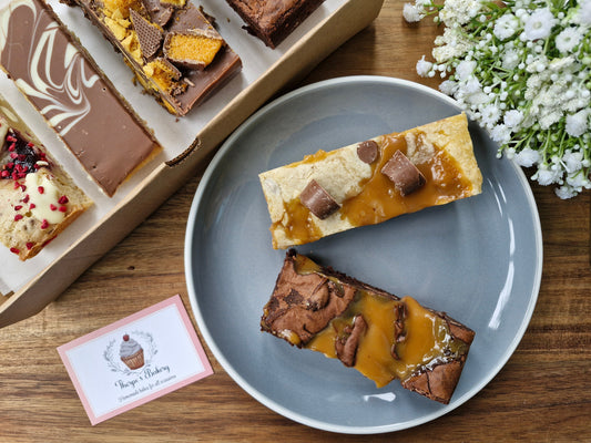 Assorted box of brownies, blondies, flapjacks and tiffins with caramel brownie & rolo blondie showcased centrally.