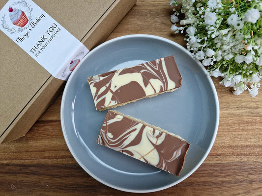 Two millionaire’s shortbread slices with marbled chocolate topping beside a Thorpe’s Bakery treat box.