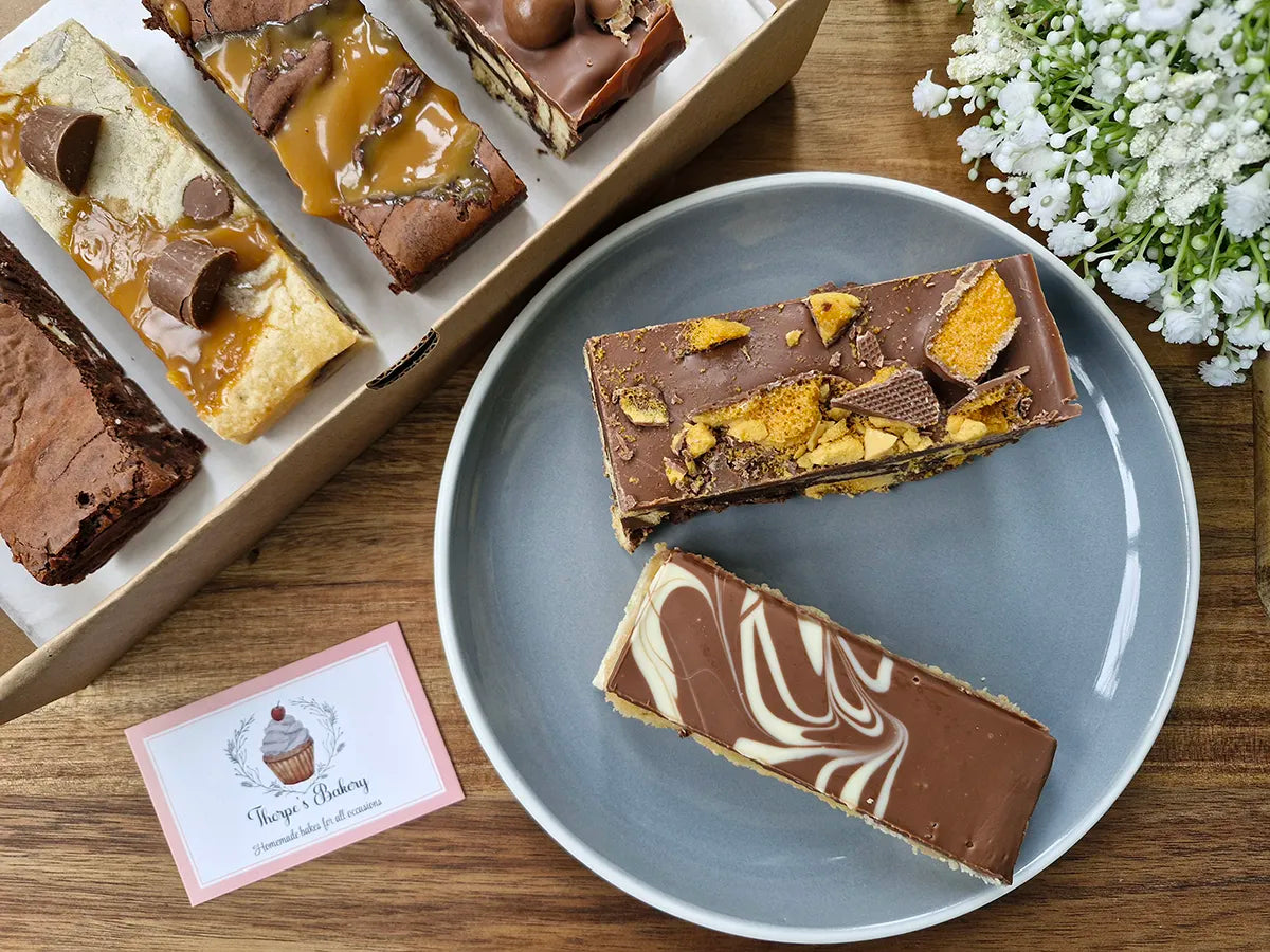 Assorted baked treats including crunchie tiffin & millionaires shortbread arranged in a gift box.