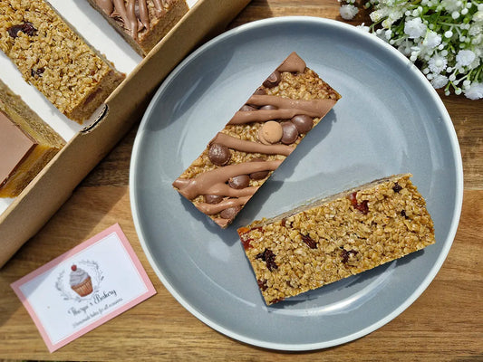 Cherry & sultana and chocolate flapjack slices on a plate beside Thorpe’s Bakery treat box.